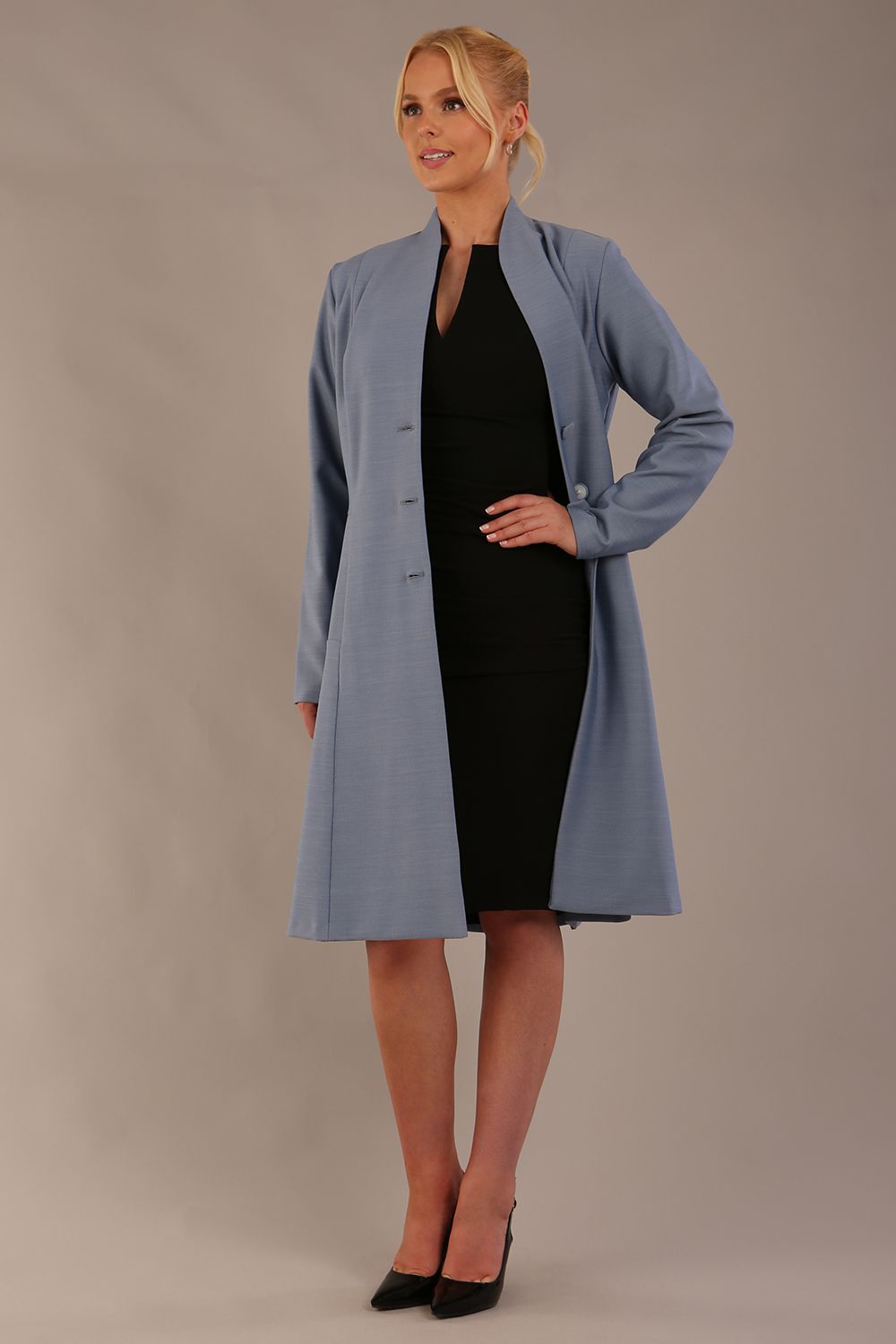 blonde model wearing diva catwalk couture fine raquella coat with buttons across the front and long sleeves with high neck and pockets in steel blue colour front (Steel Blue)