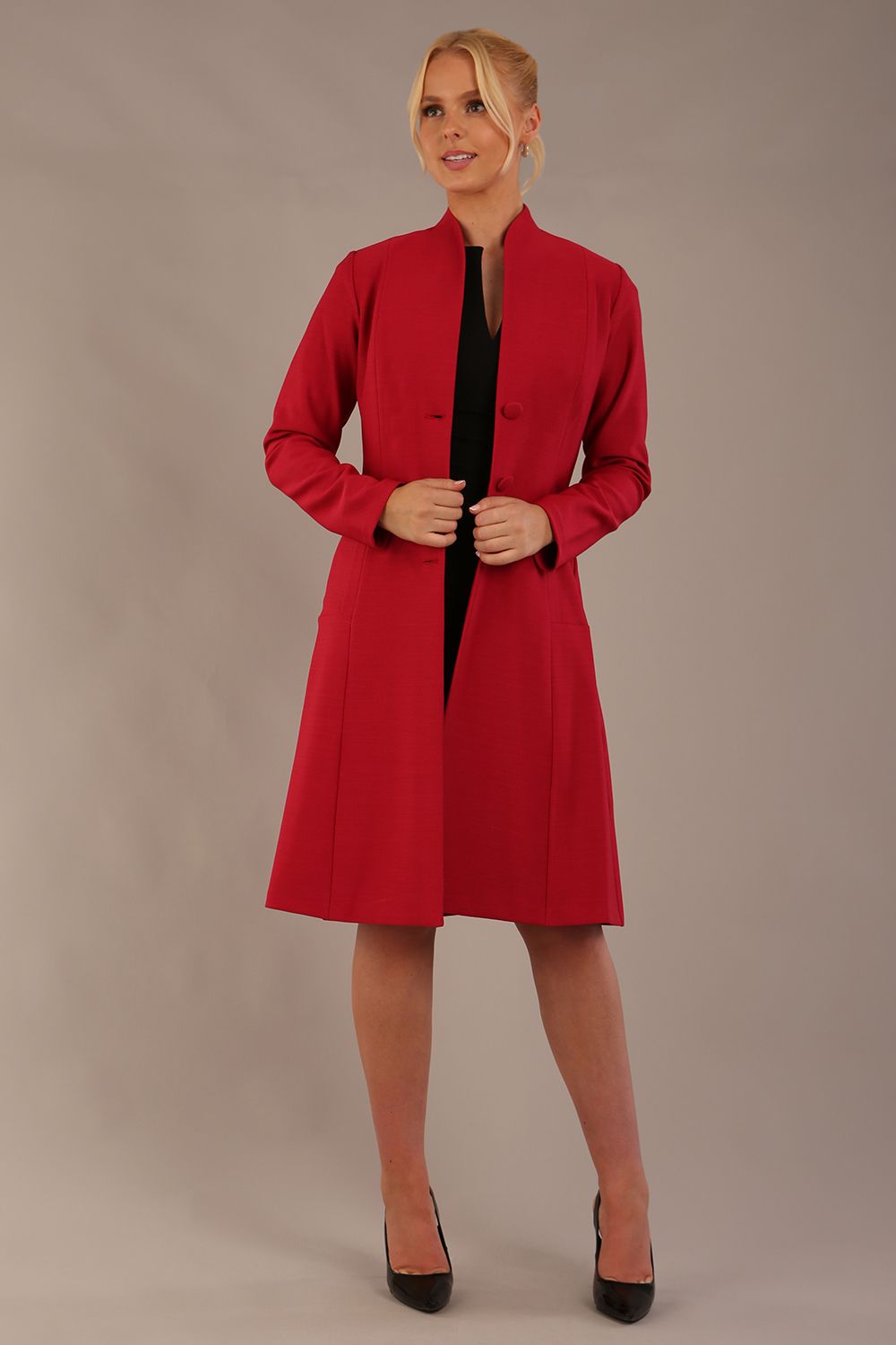 blonde model wearing diva catwalk couture fine raquella coat with buttons across the front and long sleeves with high neck and pockets in crimson pink colour front side (Crimson Pink)