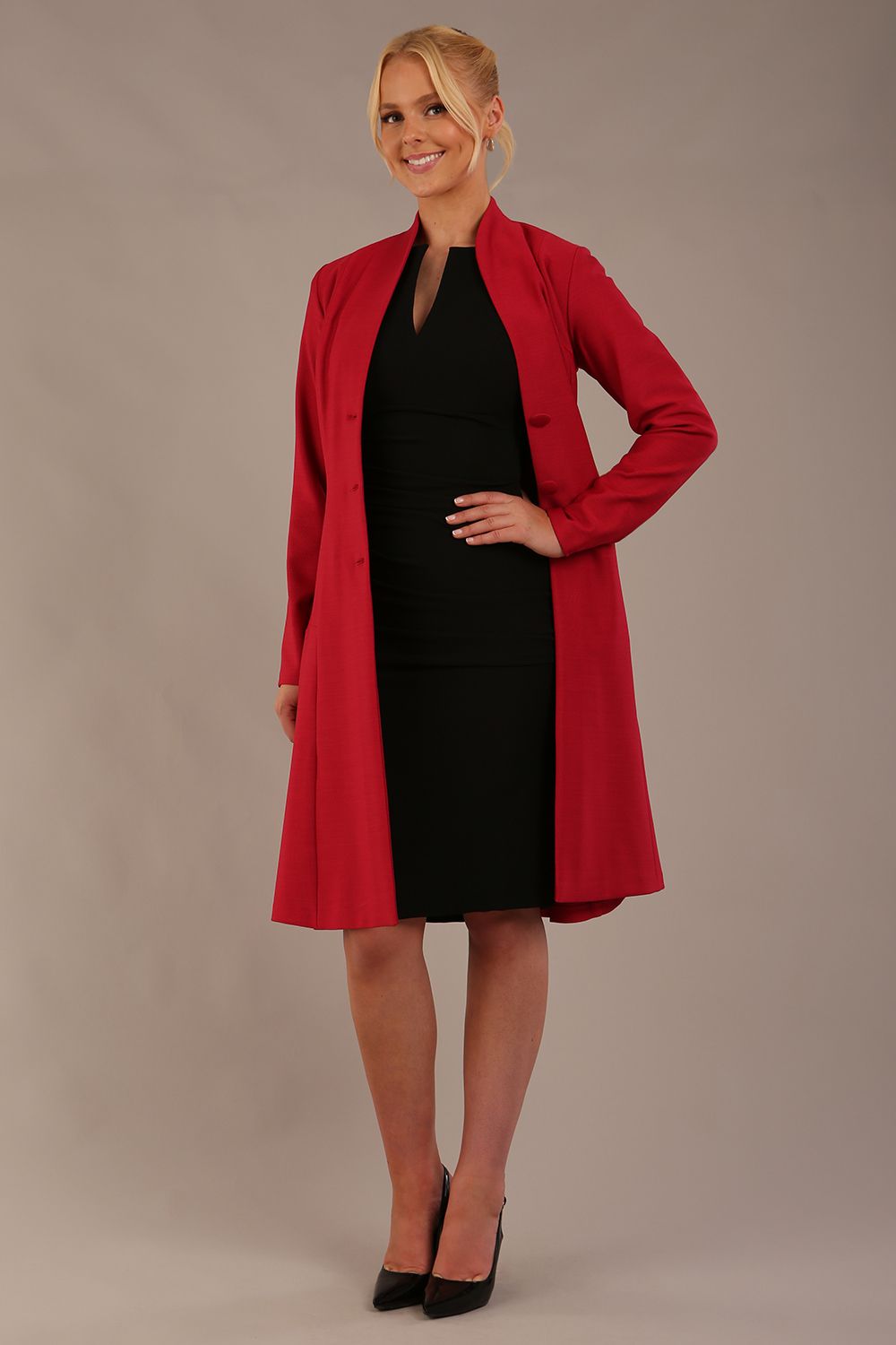 blonde model wearing diva catwalk couture fine raquella coat with buttons across the front and long sleeves with high neck and pockets in crimson pink colour front side (Crimson Pink)