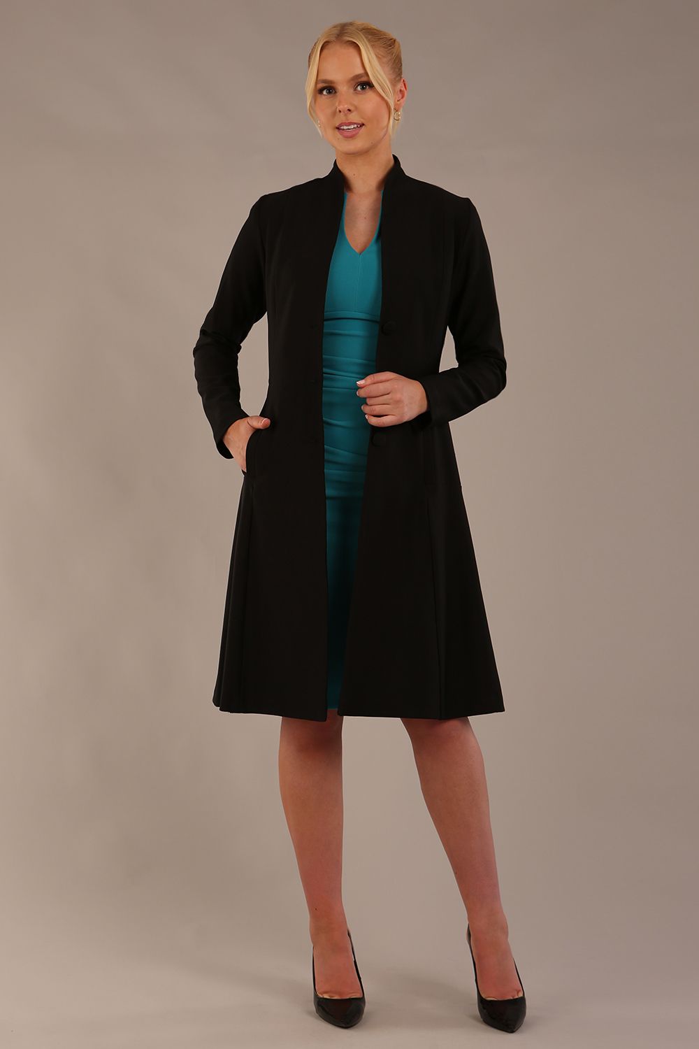 model wearing diva catwalk couture fine raquella coat with buttons across the front and long sleeves with high neck and pockets in black colour front (Black)