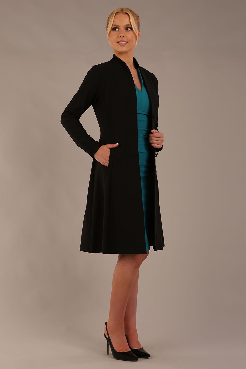 model wearing diva catwalk couture fine raquella coat with buttons across the front and long sleeves with high neck and pockets in black colour front side (Black)