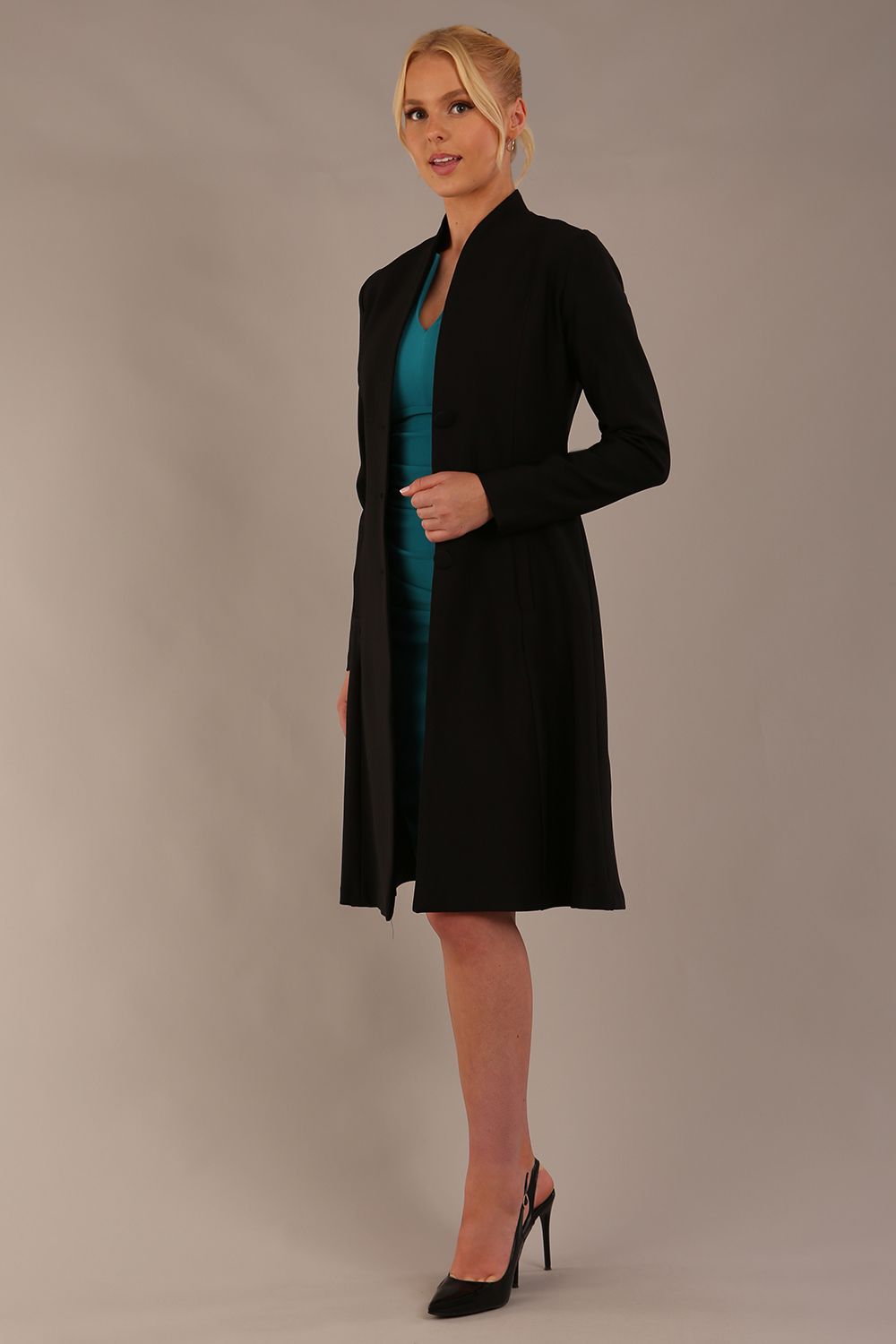 model wearing diva catwalk couture fine raquella coat with buttons across the front and long sleeves with high neck and pockets in black colour front (Black)