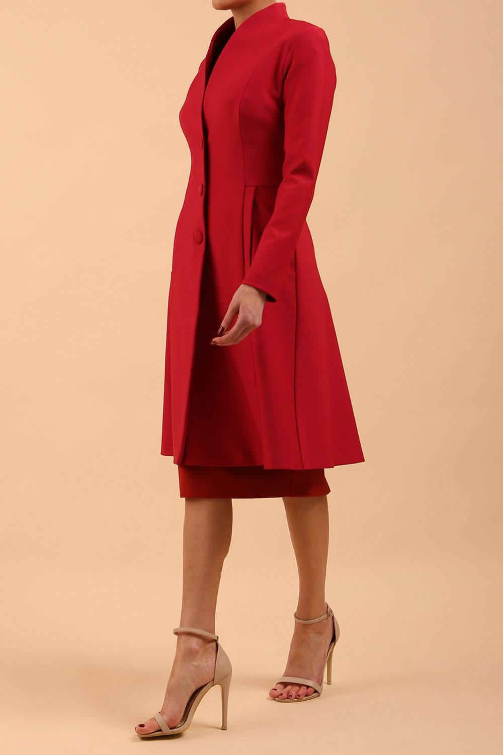 brunette model wearing diva catwalk couture fine raquella coat with buttons across the front and long sleeves with high neck and pockets in crimson pink colour front side