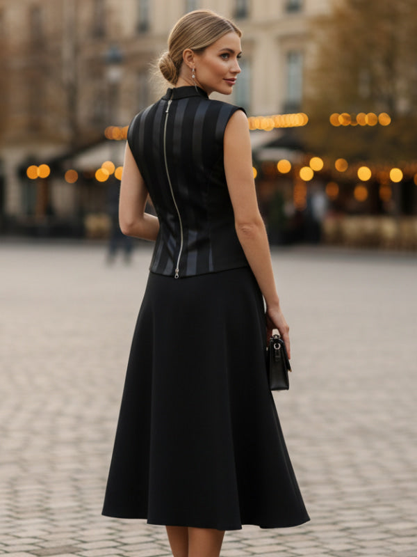 Woman in a black dress with a leather vest standing on a street with blurred lights in the background