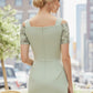 Woman in a light green dress with floral sleeves standing outdoors with blurred background (Deco Green Fern)