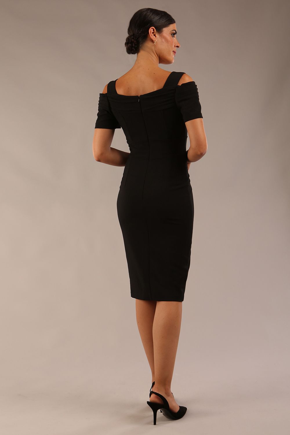 brunette model wearing diva catwalk amorette pencil skirt dress with a cold shoulder detaul and pleating across the bust and slit on a side of skirt in black back