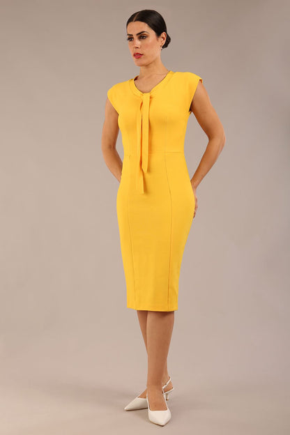brunette model wearing a diva catwalk seed lucca tie detail cap sleeves pencil dress in daffodil yellow colour front image