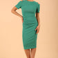 Model wearing the Diva Atlas Pencil dress with round neckline short sleeved dress with small cutouts on the shoulders in emerald green front