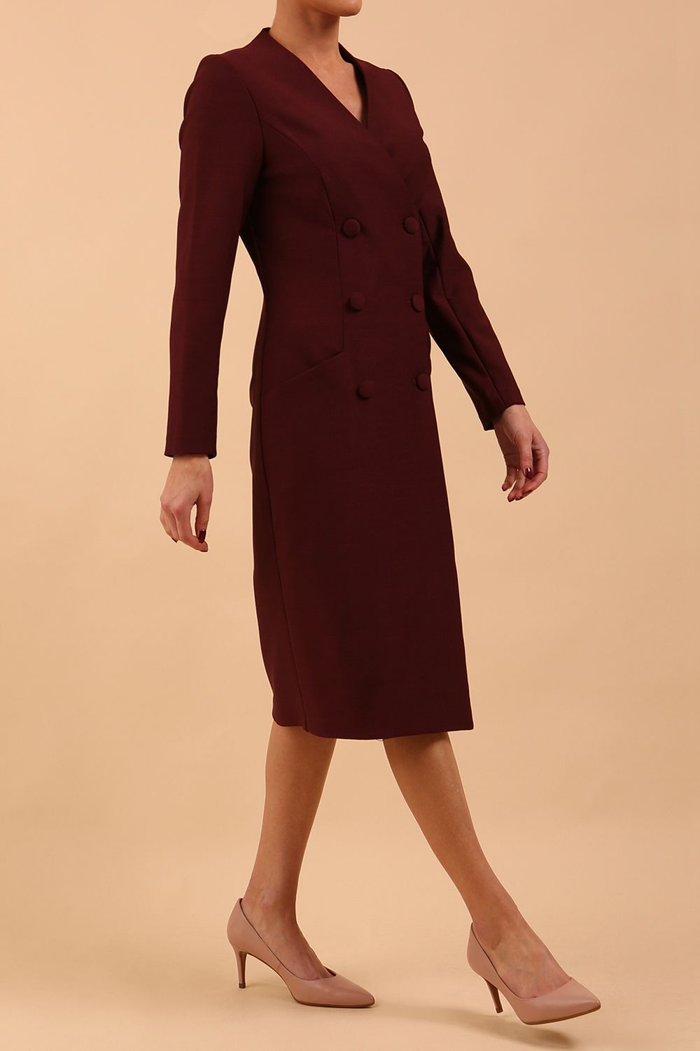 Brunette model wearing a diva catwalk Seed Silverstone Long Sleeve Coat Dress with 6 buttons across the front and pockets in colour Port Royale front side