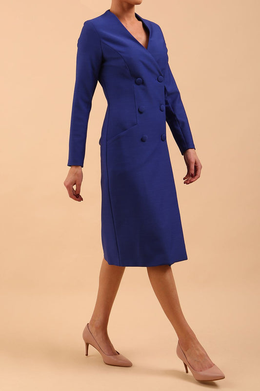 Brunette model wearing a diva catwalk Seed Silverstone Long Sleeve Coat Dress with 6 buttons across the front and pockets in colour Monaco Blue front side