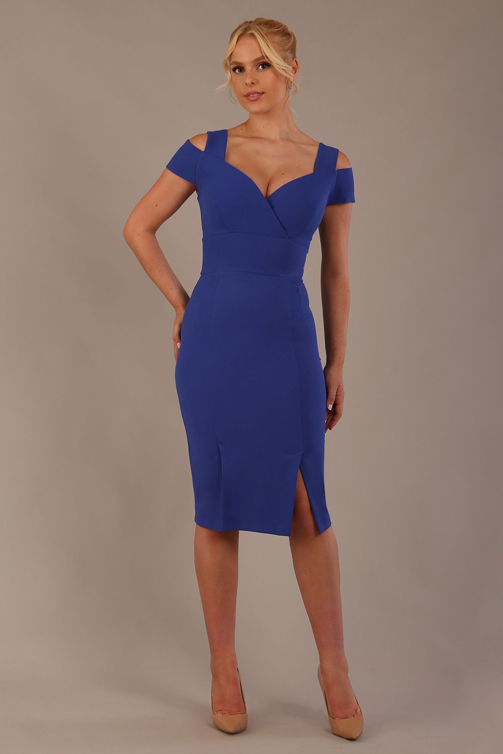 Woman wearing a riviera blue diva catwalk hayward pencil dress with short sleeves against a beige background