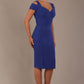 Woman wearing a riviera blue diva catwalk hayward pencil dress with short sleeves against a beige background