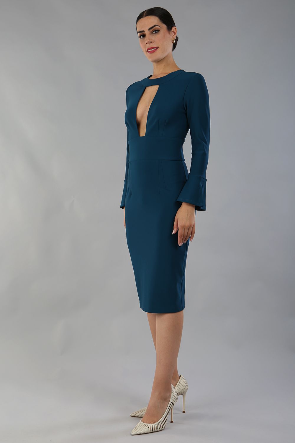 model is wearing diva catwalk fifi pencil skirt dress with three quarter flute sleeve and rounded neckline with a cut out at the front in glorious teal