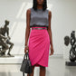 Woman in a gray top model wearing a diva catwalk Pacific Pencil Skirt with faux wrap detail and pleating on the skirt and knee length in hibiscus pink colour standing in an art gallery.