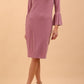 A brunette model is wearing a velvet long bell sleeve pencil dress maternity style in orchid haze colour front