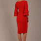A woman wearing a burnt orange knee-length diva catwalk meridian pencil dress with a round neckline, double layered peplum three quarter length sleeves, and standing against a plain background.