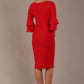 A woman wearing a electric red knee-length diva catwalk meridian pencil dress with a round neckline, double layered peplum three quarter length sleeves, and standing against a plain background back image