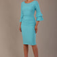A woman wearing a sky blue knee-length diva catwalk meridian pencil dress with a round neckline, double layered peplum three quarter length sleeves, and standing against a plain background.
