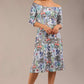 brunette model is wearing a diva catwalk islay a-line wing print dress off shoulder and knee length in water garden print front image