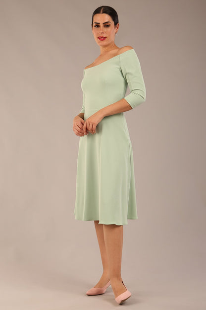 brunette model is wearing diva catwalk off shoulder swing a-line islay dress with sleeves in deco green colour front image 