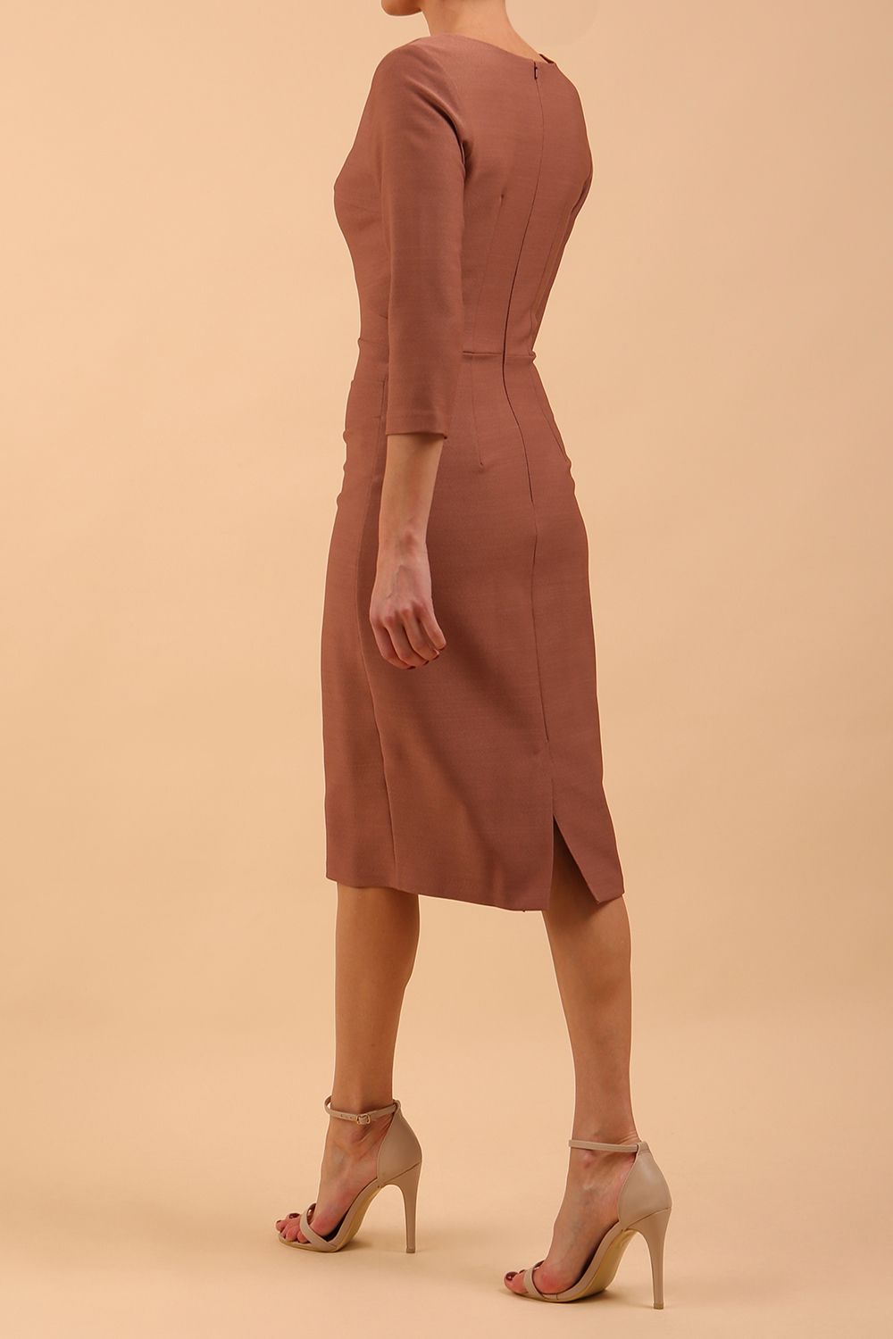 brunette model wearing diva catwalk couture althorp pencil fitted dress with sleeves and rounded neckline and bow detail at the top in acorn brown colour back side