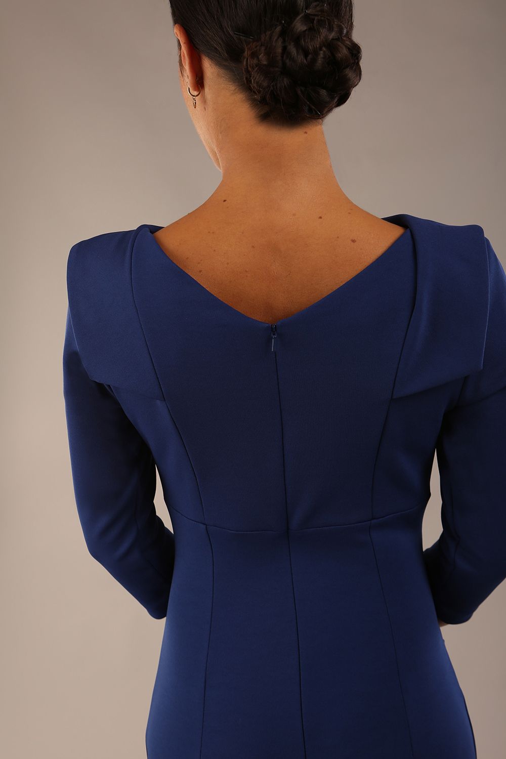 model wearing diva catwalk york pencil-skirt dress with sleeves and rounded folded collar and plearing across the tummy area in navy blue colour back close up