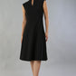 Brunette Model is wearing a sleeveless swing high neck dress with high neck in black by Diva Catwalk front