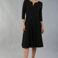 model wearing a diva catwalk Seed Corsham Swing Dress with 3/4 sleeve and below the knee length with v slit detail on the neckline in black colour