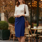 Woman in a white top and blue skirt standing in an outdoor cafe setting