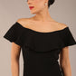 brunette model wearing diva catwalk pencil dress with off shoulder frilled front and bardot neckline in black colour front
