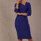 A woman modeling a palace blue diva catwalk castleford pencil dress with an asymmetric neckline, bow waistband, and pleated skirt