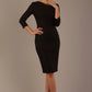 A woman modeling a black diva catwalk castleford pencil dress with an asymmetric neckline, bow waistband, and pleated skirt