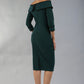 model wearing a diva catwalk Paige Bi-Stretch Dress with 3/4 sleeve, knee length, Fold over off-shoulder neckline with bow detail and with Contrast piping on sleeve cuffs and neckline in Forest Green and black colour