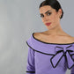 model wearing a diva catwalk Paige Bi-Stretch Dress with 3/4 sleeve, knee length, Fold over off-shoulder neckline with bow detail and with Contrast piping on sleeve cuffs and neckline in Lilac Wisteria and black colour