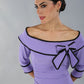 model wearing a diva catwalk Paige Bi-Stretch Dress with 3/4 sleeve, knee length, Fold over off-shoulder neckline with bow detail and with Contrast piping on sleeve cuffs and neckline in Lilac Wisteria and black colour