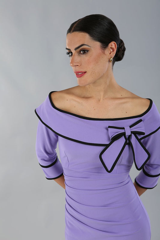 model wearing a diva catwalk Paige Bi-Stretch Dress with 3/4 sleeve, knee length, Fold over off-shoulder neckline with bow detail and with Contrast piping on sleeve cuffs and neckline in Lilac Wisteria and black colour