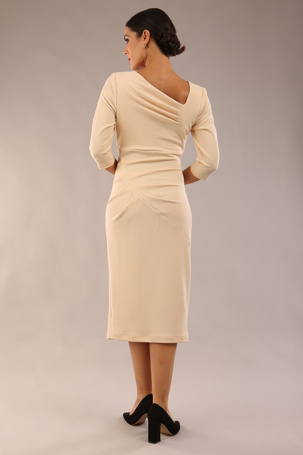 model wearing a diva catwalk Rococo 3/4 Sleeved Pencil Dress with asymmetric neckline with pleating details and 3/4 sleeves length and knee length in beige colour