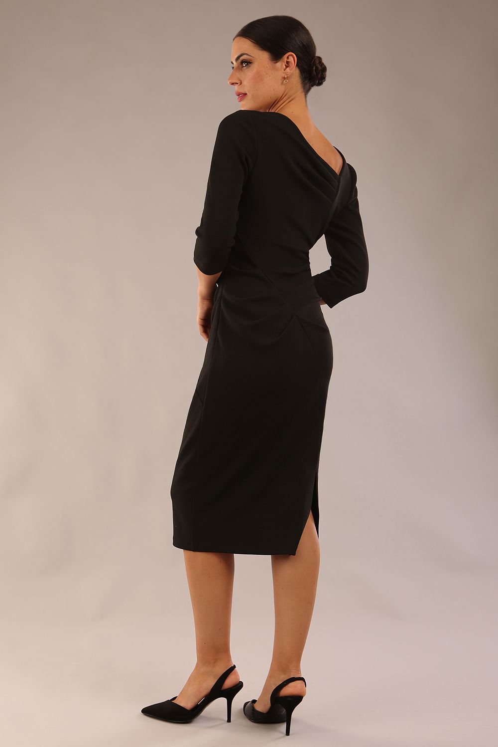 model wearing a diva catwalk Rococo 3/4 Sleeved Pencil Dress with asymmetric neckline with pleating details and 3/4 sleeves length and knee length in black colour