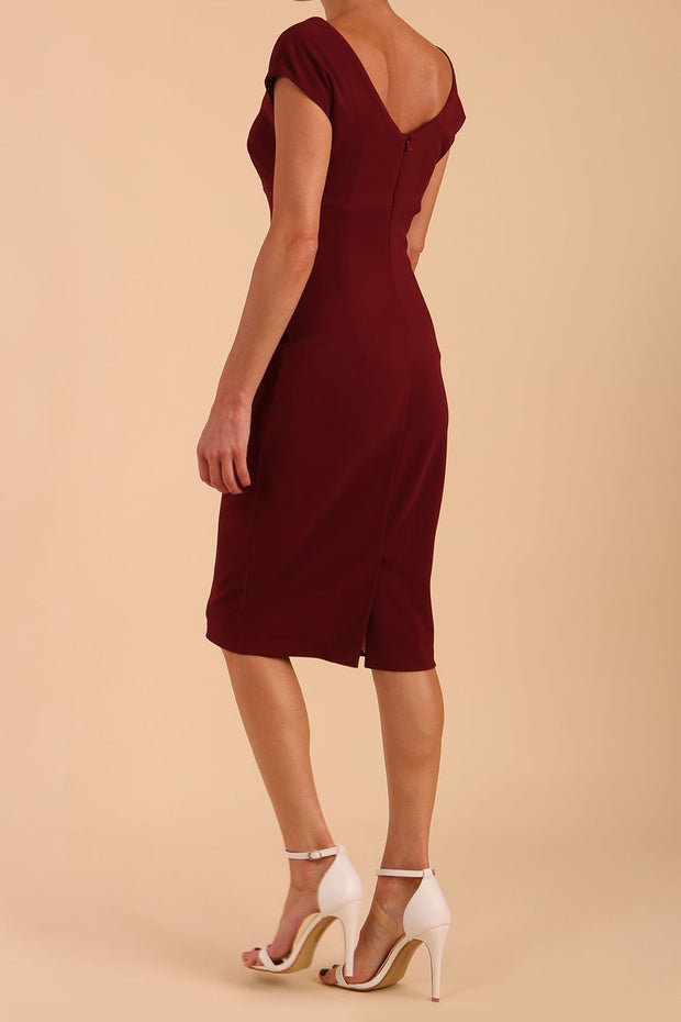 Model wearing Diva Catwalk Polly Rounded Neckline Pencil Cap Sleeve Dress with pleating across the tummy area in Cabaret Burgundy back