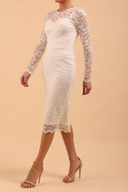 Model wearing a diva catwalk Montana Lace Dress with long lace sleeve and knee length with round lace neckline  in Ivory Cream colour front side