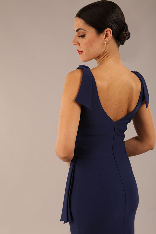Model wearing diva catwalk Malvern Sleeveless Pencil Wiggle Dress with tie detail at waist and shoulders in Navy Blue colour back detail close up open back