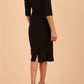 model wearing seed couture royale pencil skirt dress with pleating across the tummy area with rounded neckline with a split in the middle and 3 4 sleeve in Black colour back