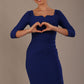 model is wearing a diva catwalk hathaway sweetheart neckline pencil dress in cobalt blue front view making a heart shape with her hands against a plain background
