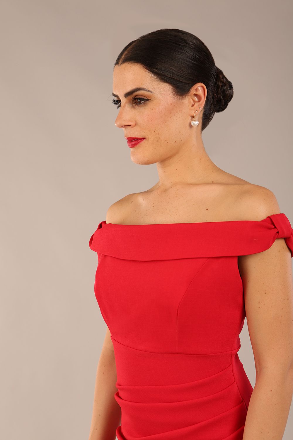 brunette model wearing a diva catwalk cloud pencil fitted flattering dress off shoulder sleeveless with detail with pleating around the front in scarlet red front close up