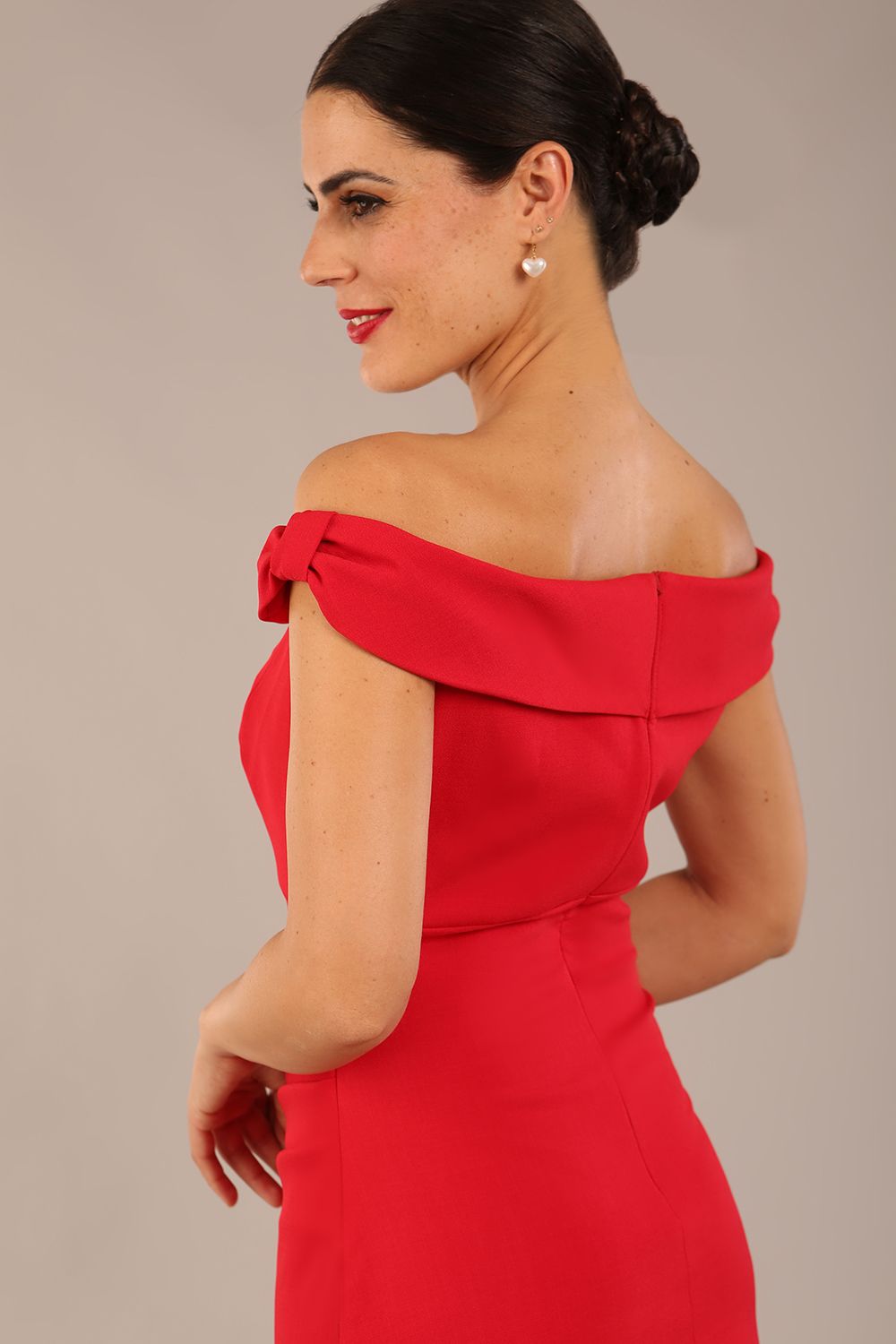 brunette model wearing a diva catwalk cloud pencil fitted flattering dress off shoulder sleeveless with detail with pleating around the front in scarlet red back close up