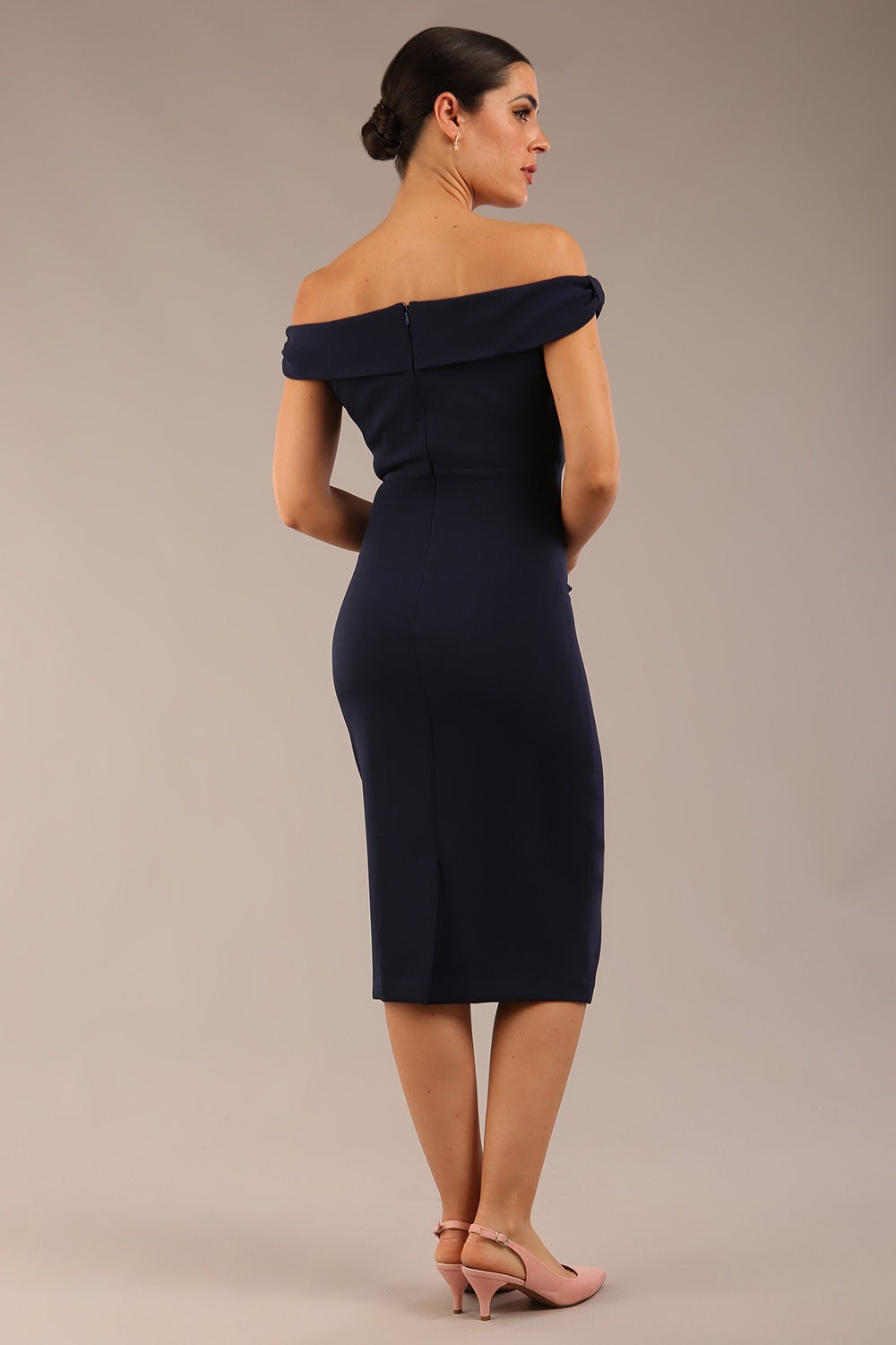 brunette model wearing a diva catwalk cloud pencil fitted flattering dress off shoulder sleeveless with detail with pleating around the front in navy blue back