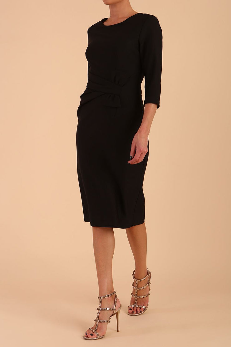 Model wearing diva catwalk Seed Andante Pencil Skirt Dress with 3/4 sleeve and bow detail at waistline in Black front side