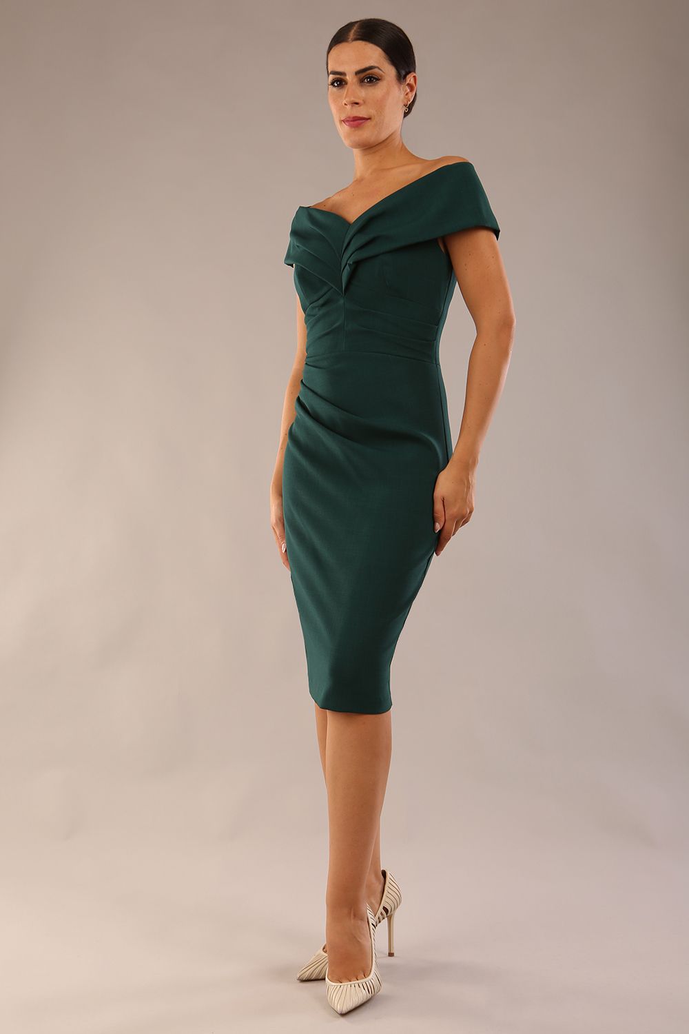 Model is wearing an off shoulder pencil dress by Diva Catwalk in forest green