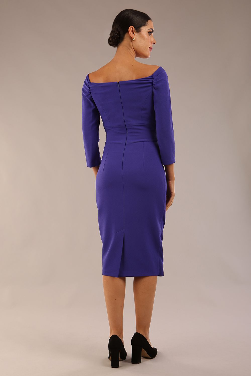 brunette model wearing diva catwalk evening pencil dress off shoulder with sleeves and pleated pencil skirt in colour spectrum indigo back