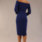 brunette model wearing diva catwalk evening pencil dress off shoulder with sleeves and pleated pencil skirt in colour oxford blue back